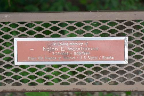 A memorial badge on one of the benches facing the river.